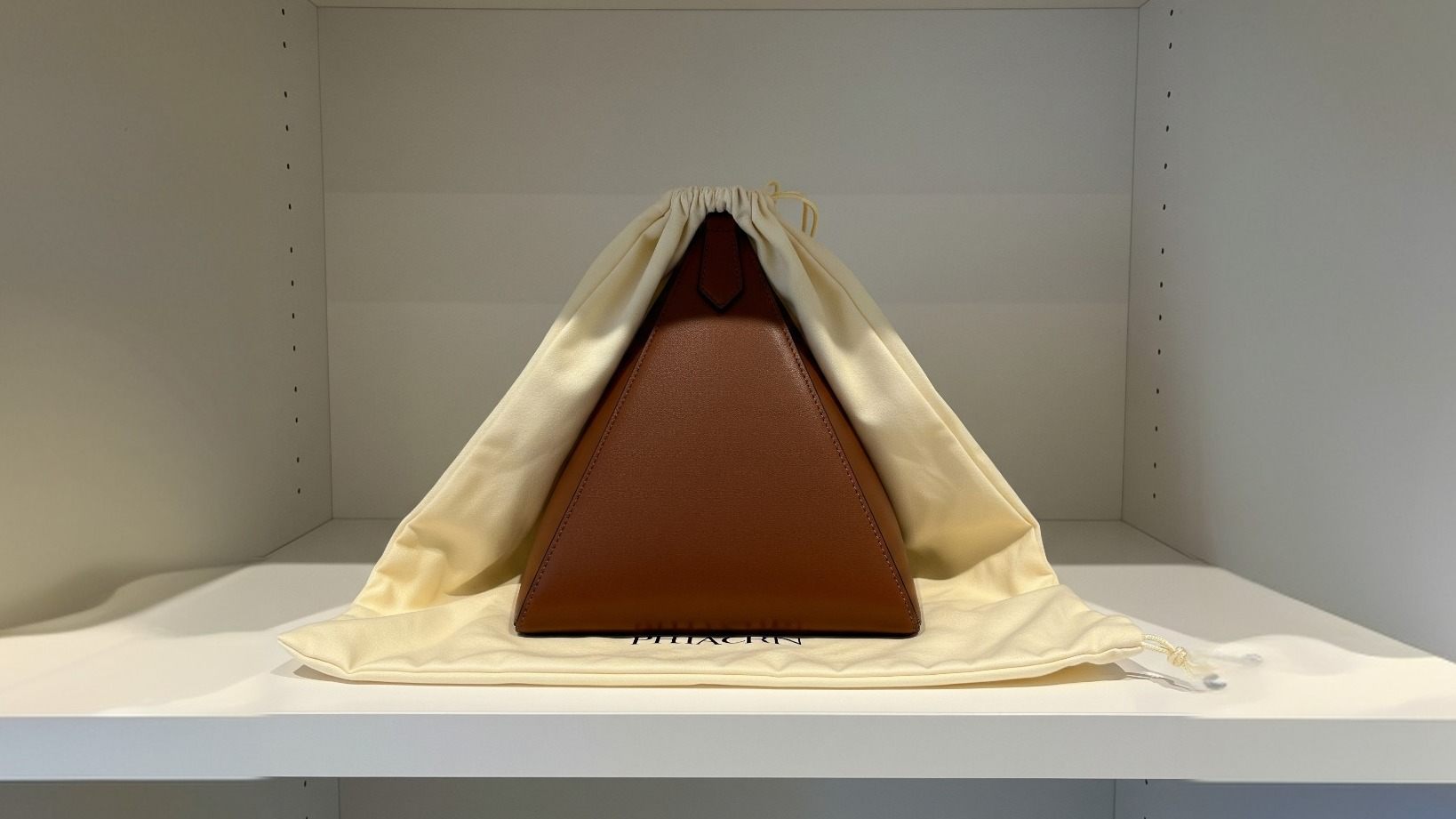 Stylish pyramid purse on shelf with protective storage setup